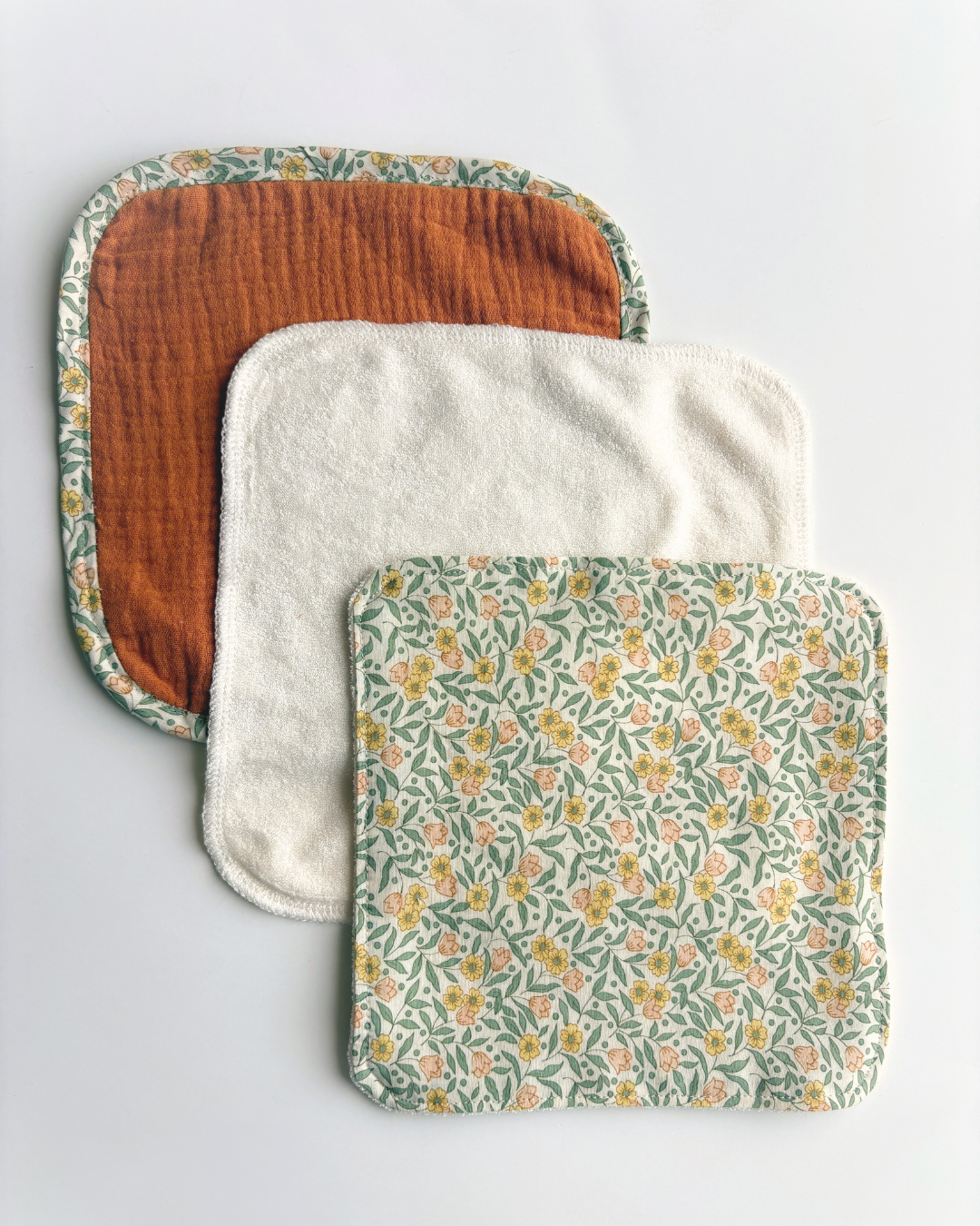 Three washcloths arranged in an overlapping stack on a light gray background. 3 finishing options: Topstitch, overlock or bias