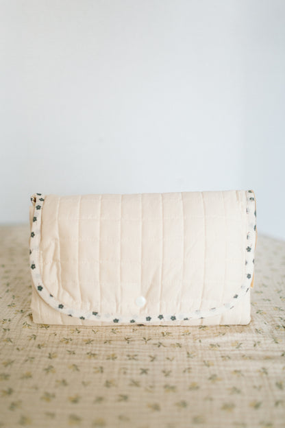 Handmade quilted portable changing mat with snap button closure and floral trim.
