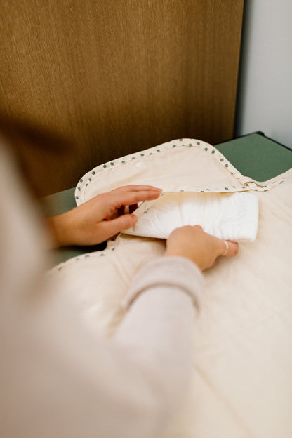 Hands placing a white diaper inside a handmade portable changing mat.