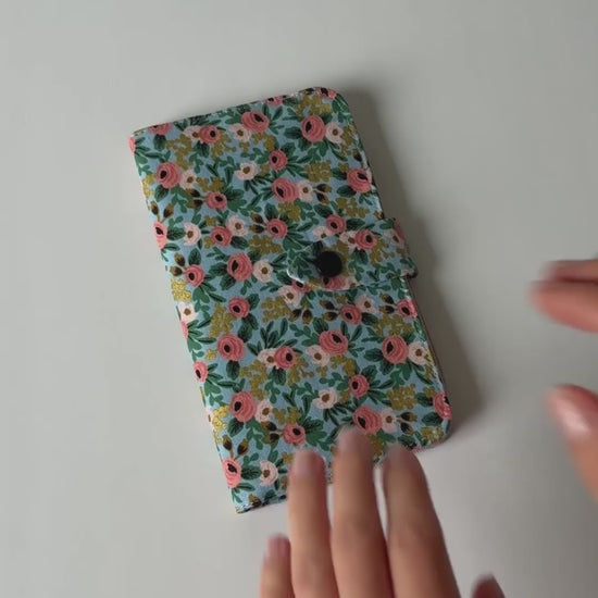 Video showing a fabric health record cover from the outside and inside, featuring four interior pockets and a snap closure.