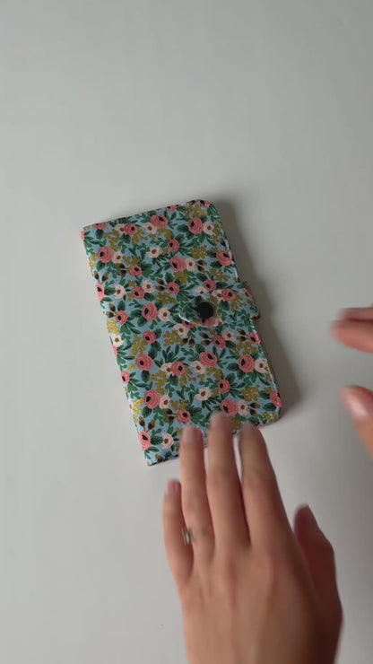 Video showing a fabric health record cover from the outside and inside, featuring four interior pockets and a snap closure.
