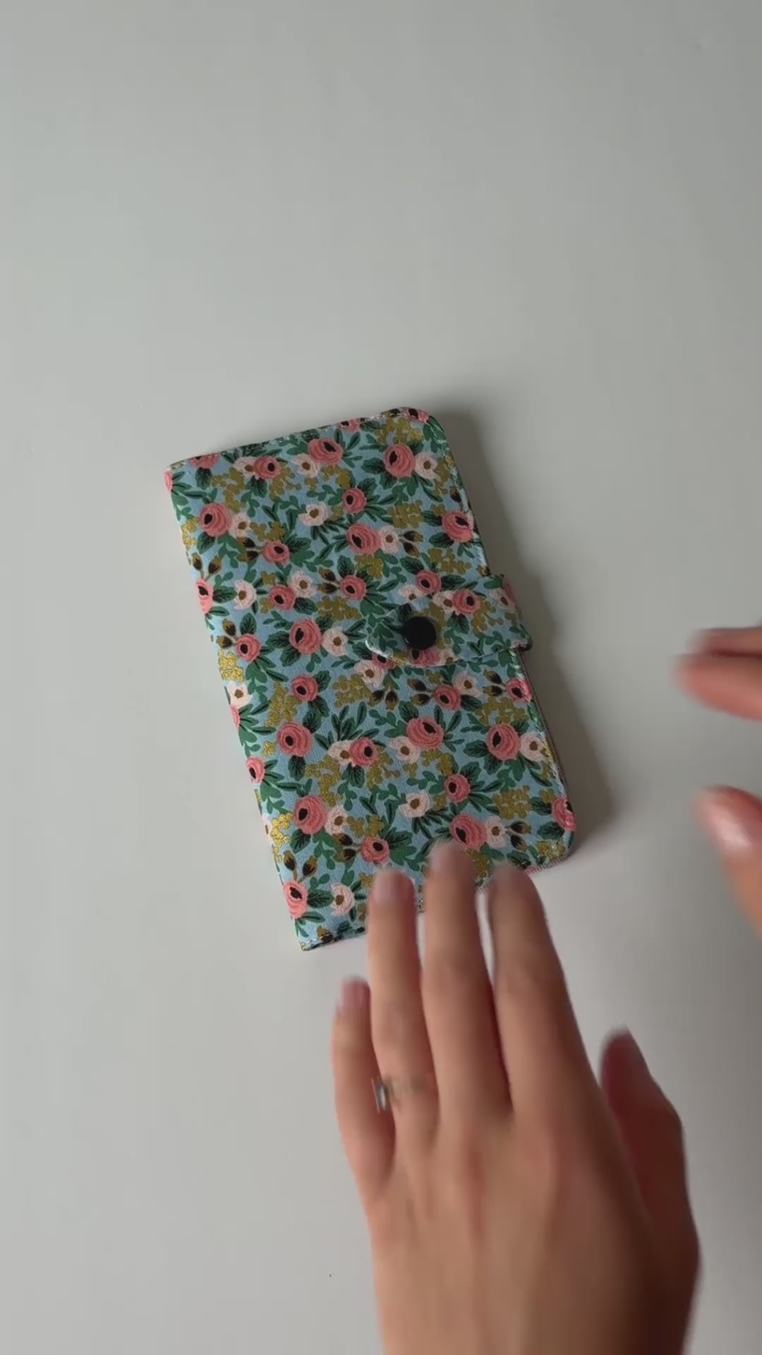 Video showing a fabric health record cover from the outside and inside, featuring four interior pockets and a snap closure.