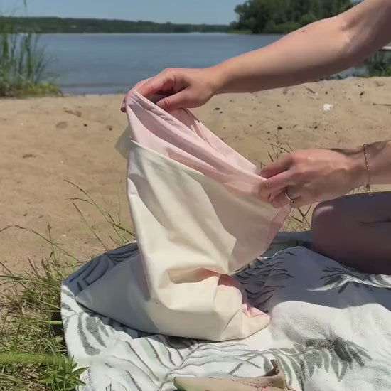 A girl placing water shoes into a waterproof bag and closing it with a zipper. Text reads: “POV: You sew the perfect wet bag for the beach.”