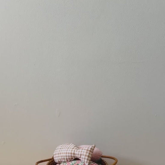 A hand holding a wooden fishing rod with a worm attached to the end, catching colorful fabric fish in a wicker basket.
